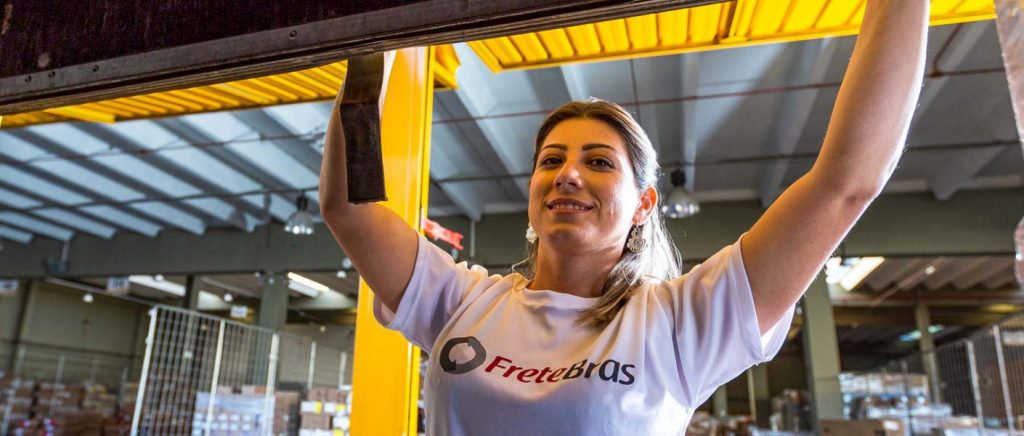 A imagem mostra uma mulher trabalhando em um pátio. Ela está com uma camiseta com o logotipo da Fretebras, representando uma empresa parceira que faz parte da história da Fretebras.