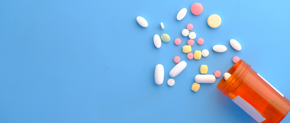 Frasco com remédios coloridos espalhados, ilustrando o gerenciamento de risco no transporte de medicamentos.