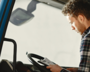 Motorista de caminhão lendo papel que ilustra os documentos de transporte obrigatórios.