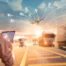 Homem com tablet na mão e caminhões ao fundo na estrada mostra como é a digitalização de transportadoras.