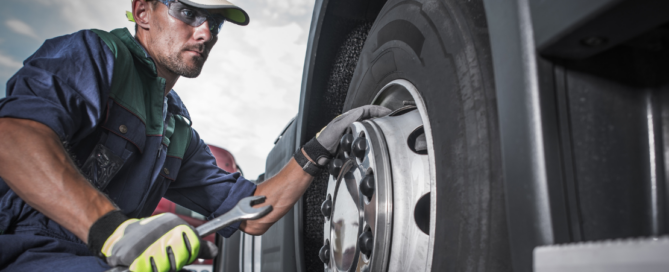 Mecânico mexendo na roda do caminhão, ilustra a diferença entre manutenção preventiva, preditiva e corretiva.