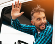 Motorista dentro de caminhão acenando, ilustra a atualização da Tabela de frete ANTT 2024.