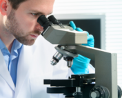Homem em microscópio ilustra exame toxicológico gratuito no SUS.