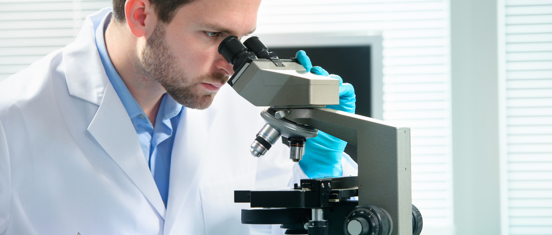 Homem em microscópio ilustra exame toxicológico gratuito no SUS.