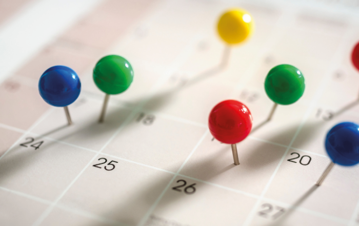 Um calendário está com vários pins coloridos sobre ele, representando marcações de imprevistos e oportunidades que uma transportadora precisa lidar.