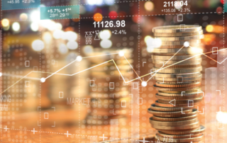 Em primeiro plano, tem várias moedas douradas empilhadas. Além disso, vários gráficos em linhas estão sobrepondo a imagem, mostrando os altos e baixos do ciclo financeiro e do fluxo de caixa.