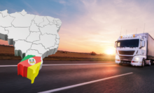 A imagem mostra ao lado direito um caminhão branco em uma estrada, rumo ao Rio Grande do Sul, representando os melhores tipos de cargas na região. Do lado esquerdo tem um mapa do Brasil com o estado do RS destacado pela sua bandeira.