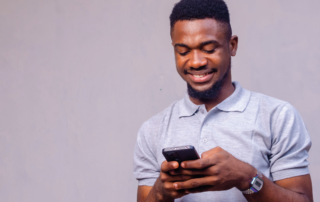 A imagem mostra um homem mexendo no celular, representando um motorista que quer saber sobre a empresa que oferece um frete.