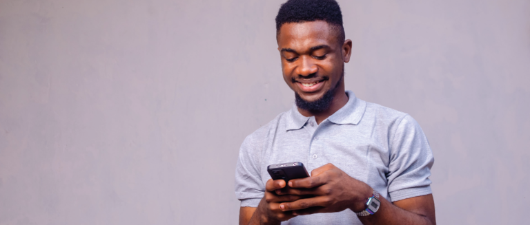 A imagem mostra um homem mexendo no celular, representando um motorista que quer saber sobre a empresa que oferece um frete.